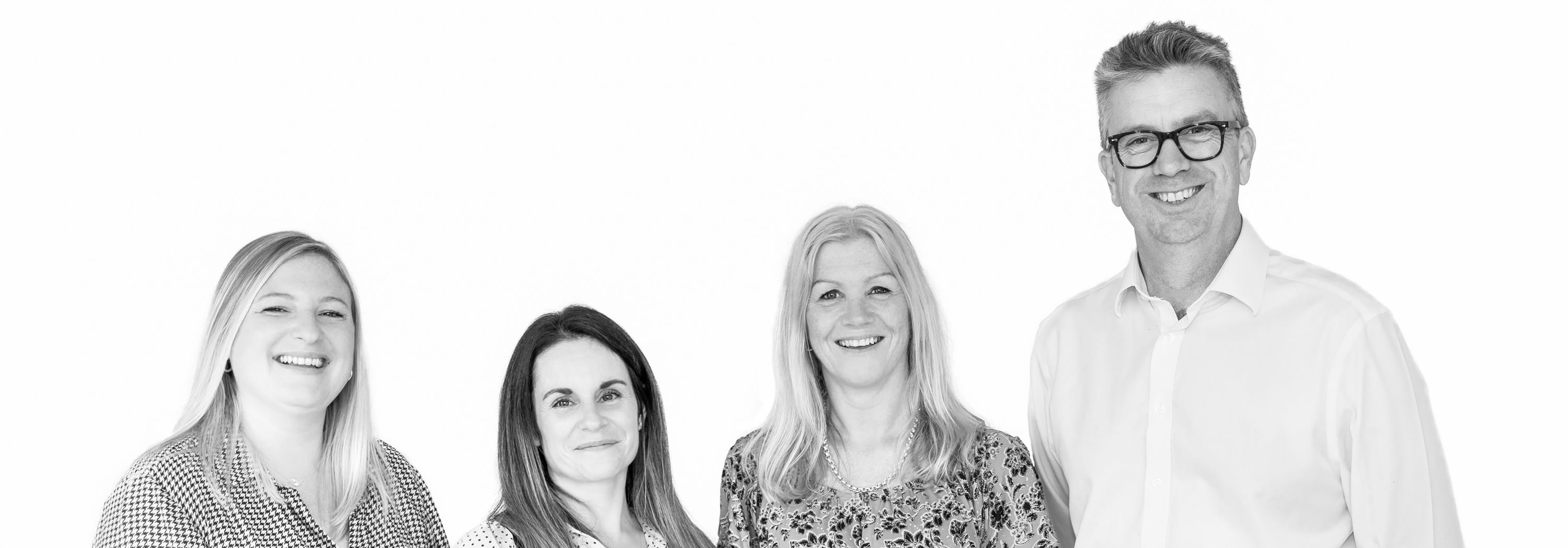 Black and White photo of Laura Ramm, Emily Bland, Tina Heale and Simon Dunscombe Employees at itecopeople stood in a line smiling